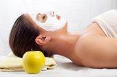 image of facial  - Beautiful young woman lying on massage table with natural facial mask on her face - JPG 