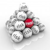 pic of investment  - A pyramid of stacked balls each marked Risk with one reading Reward symbolizing the hidden benefits of taking a risk and overcoming a challenge with a great return on your investment of effort - JPG 