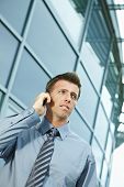foto of business people  - Serious businessman standing outdoor talking on mobile phone - JPG 