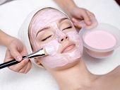 stock photo of facial  - Young beautiful girl receiving pink facial mask in spa beauty salon  - JPG 