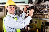 stock photo of industrial  - happy male electrician working on industrial machine - JPG 