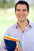 image of outdoor  - Happy male student holding notebooks outdoors looking casual - JPG 