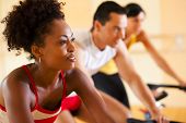 picture of health  - three people in the gym exercising on cycles - JPG 