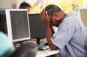 stock photo of pressure  - Stressed Man Working At Desk In Busy Creative Office - JPG 