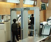 stock photo of security  - airport security check with passenger walking through metal detector - JPG 