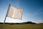 stock photo of golf  - A golf flag blowing in the wind on a sunny afternoon - JPG 