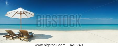 Picture or Photo of Panoramic view of two chairs and white umbrella on the beach. Banner lots of copy space