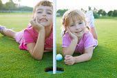 picture of golf  - Golf two sister girls relaxed lying near green hole with ball - JPG 