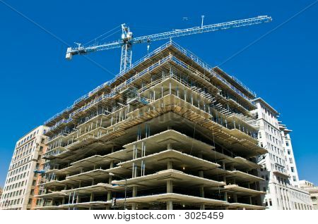 Picture or Photo of Modern urban building under construction with a crane and blue sky