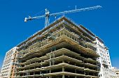 foto of construction  - modern urban building under construction with a crane and blue sky - JPG 