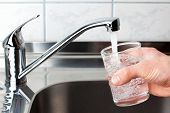 stock photo of pour  - Hand holding a glass of water poured from the kitchen faucet - JPG 