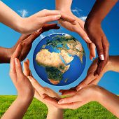 pic of globe  - Conceptual peace and cultural diversity symbol of multiracial hands making a circle together around the world the Earth globe on blue sky and green grass background - JPG 