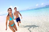 stock photo of holidays  - Couple running on a sandy beach - JPG 