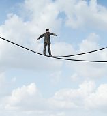 picture of dilemma  - Risky choice business concept with a man walking a dangerous high wire tightrope that is in a crossroads splitting into two opposite directions as a symbol of strategy dilemma deciding on the best path - JPG 