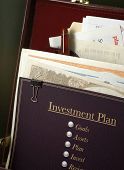 foto of investment  - investment plan with planning process outlined in briefcase ready for review with stocks and planning paperwork behind the plan - JPG 