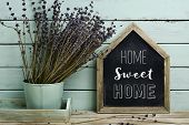 closeup of a house-shaped chalkboard with the text home sweet home written in it and a bunch of lave