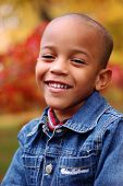 stock photo of africanamerican  - young boy smiles as he poses in front of a beautiful autumn backdrop - JPG 