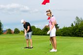 stock photo of golf  - Young sportive couple playing golf on a golf course - JPG 