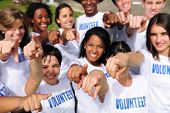 pic of group  - portrait of a happy and diverse volunteer group pointing towards camera - JPG 