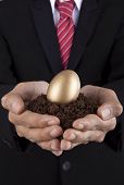 picture of investment  - Investment concept businessman holding a golden egg and soil - JPG 