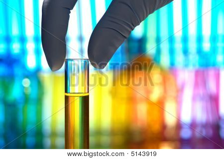 Picture or Photo of Scientist hand holding a glass test tube filled with liquid for an experiment in a science research lab