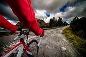 foto of competition  - Cyclist on road bike through a asphalt road in the mountains and blue sky with clouds - JPG 