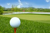 picture of golf  - close up of a golf ball on tee with beautiful golf course as background - JPG 
