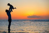 picture of sunset  - Father and little daughter silhouettes on beach at sunset - JPG 