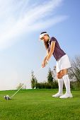 stock photo of golf  - Female golfer getting ready to hit the ball on golf course - JPG 