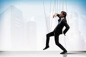 picture of businessmen  - Image of businessman hanging on strings like marionette against city background - JPG 