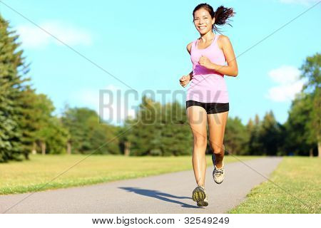 Picture or Photo of Sport fitness woman running in park on summer day. Asian female runner during outdoor workout. Fit sport fitness model of mixed Asian / Caucasian ethnicity.