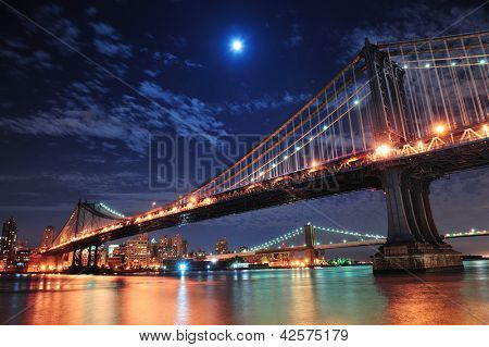 Picture or Photo of Brooklyn Bridge and Manhattan Bridge over East River at night with moon in New York City Manhattan with lights and reflections.