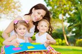 foto of children  - Image of cute young female with two little children read book outdoors - JPG 