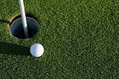 picture of golf  - A white golf ball near the hole of a golfing green or course - JPG 