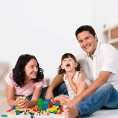 stock photo of home  - Happy family with parents and daughter playing with colorful blocks inside at home - JPG 