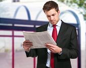 picture of newspaper  - A businessman reads the finance newspaper while waiting for bus - JPG 