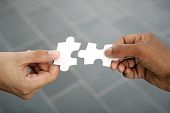 image of puzzle  - Hands trying to fit two puzzle pieces together - JPG 