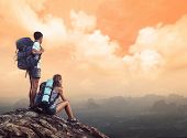 stock photo of valley  - Two hikers with backpacks standing on top of a mountain and enjoying a valley view - JPG 