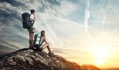 stock photo of group  - Two tourists with backpacks enjoying sunset on top of a mountain - JPG 