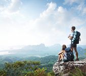 picture of valley  - Hikers with backpacks enjoying valley view from top of a mountain - JPG 