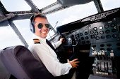 image of transportation  - Male pilot sitting in an airplane cabin flying and smiling - JPG 