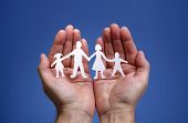 stock photo of security  - Cutout paper chain family with the protection of cupped hands - JPG 