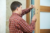 stock photo of industrial  - Male handyman carpenter at interior wood door lock installation - JPG 