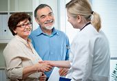stock photo of handshake  - senior couple visiting a doctor at the doctor - JPG 