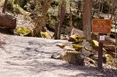 A warning sign next to a hiking trail in the forest