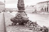 stock photo of bridge  - Lamppost Base and the Ponte Vecchio Bridge with River Arno Florence Italy in Black and White Sepia Tone - JPG 