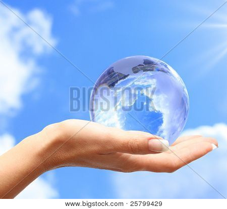 Picture or Photo of Globe in human hand against blue sky. Environmental protection concept.