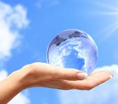 foto of globe  - Globe in human hand against blue sky - JPG 