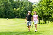 foto of golf  - Young sportive couple playing golf on a golf course - JPG 
