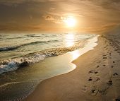 stock photo of sunset  - golden sunset on the sea shore and footprints in the sand - JPG 